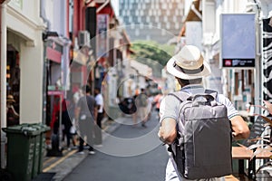 Young man hipster traveling with backpack and hat, happy Asian traveler walking at Haji Lane and Arab street in Singapore.