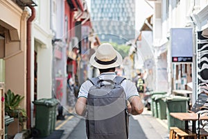 Young man hipster traveling with backpack and hat, happy Asian traveler walking at Haji Lane and Arab street in Singapore.