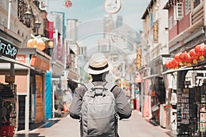 Young man hipster traveling with backpack and hat, happy Solo traveler walking at Chinatown street market in Singapore. landmark photo