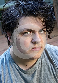 Young man in his 20`s with dark hair relaxed and happy outdoors in summer