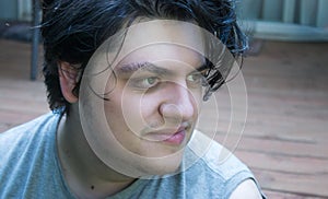 Young man in his 20`s with dark hair relaxed and happy outdoors in summer