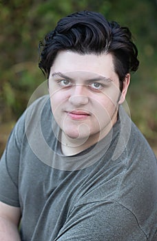 Young man in his 20`s with dark hair relaxed and happy outdoors in summer