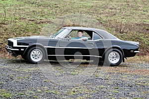 A young man in his 68 Camaro.