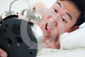 Young man on his bedside, knowing that he overslept and late for