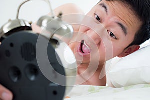 Young man on his bedside, knowing that he overslept and late