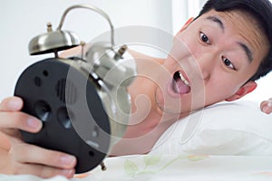 Young man on his bedside, knowing that he overslept and late for his schedule.