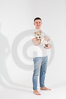 Young man with his dog at studio. Young owner hugs his pet. young and beautiful man holding his dog in his arms with