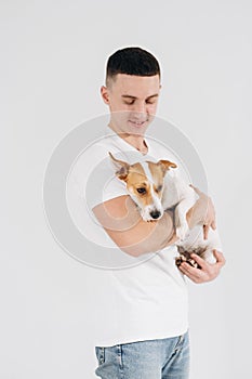 Young man with his dog at studio. Young owner hugs his pet. young and beautiful man holding his dog in his arms with