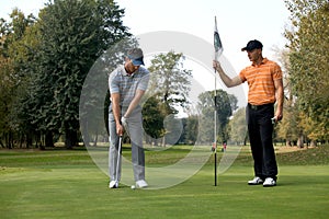 Young man with his friend playing golf in golf course