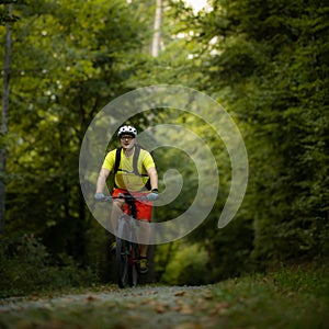 Young man with his mountain bike going for a ride past the city limits in a lovely forest