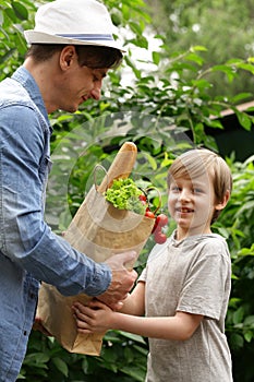 Young man and his son with a paper bag shopping organic natural food