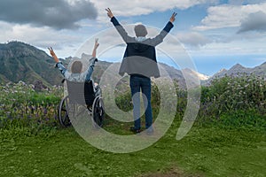 Young man and his wife in wheelchair travelling together by car in mountains