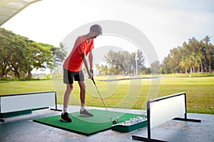 Young man hitting ball on golf driving range