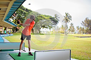 Young man hitting ball on golf driving range