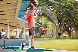 Young man hitting ball on golf driving range