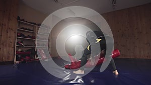 Young man hitting dummy punching bag in gym during practicing combat technique