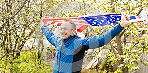 Young man holding american national flag to the sky with two hands