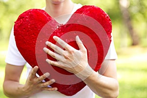 Young man holding big red heart