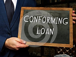 Young man holding a black chalkboard in hands. Conceptual photo about CONFORMING LOAN with written text