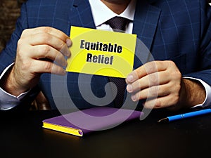 Young man holding a blank card in hands. Conceptual photo about Equitable Relief with written text