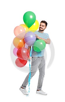 Young man holding bunch of colorful balloons