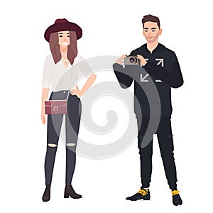 Young man holding camera and making photo of his girlfriend. Fashionable romantic couple. Funny cute male and female