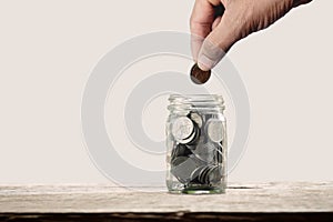 Young man holding coins putting in The bottle glass. concept saving money or tax save for financial accounting and business