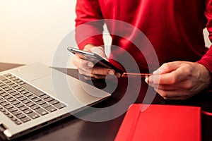 Young man holding a credit card and using the smart phone for making a secure payment online