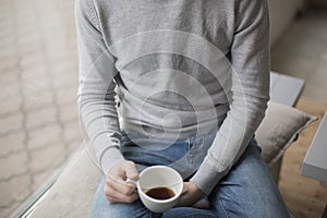 Young man holding cup of coffee inside the coffee shop