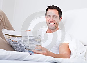 Young Man Holding Cup In Hand Reading Newspaper