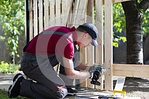 Young man holding drill-drive. Carpenter works