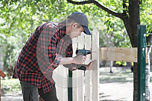 Young man holding drill-drive. Carpenter works