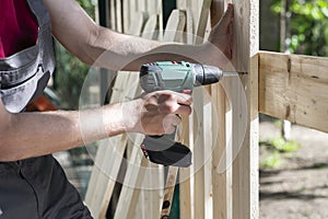 Young man holding drill-drive. Carpenter works