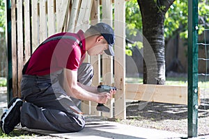 Young man holding drill-drive. Carpenter works with electrical planer