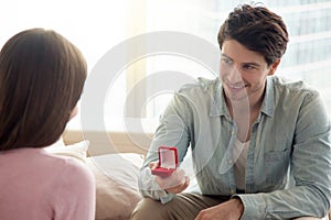 Young man holding engagement ring, making marriage proposal to g