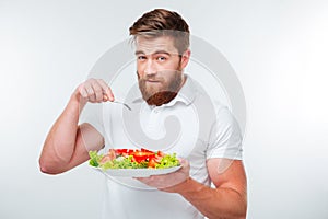 Young man holding fork to eat fresh vegetable salad meal