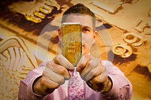 Young businessman holding a gold bar