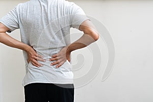 Young man holding his back in pain. Medical concept