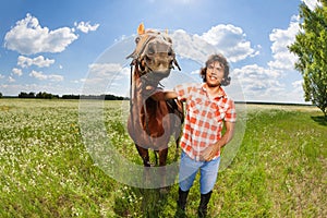 Young man holding his beautiful horse by a bridle