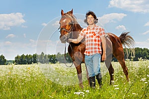 Young man holding his brown horse by a bridle