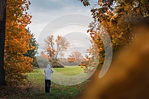 Young man holding his white hoodie and standing in autumn Czech landscape