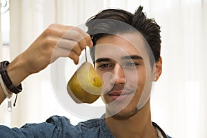 Young man holding a large ripe yellow pear