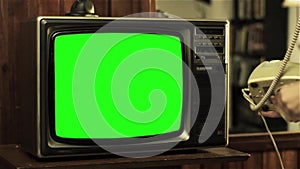 Young Man holding Old Telephone and Watching Retro TV Green Screen. Closeup.