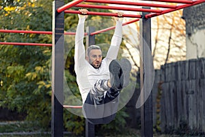 Young man holding onto a horizontal ramp working out his frontal abs, abs workout with horizontal ladder