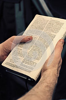 Young man holding an open bible, reading and taking notes