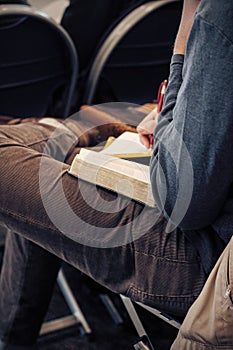Young man holding an open bible, reading and taking notes