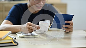 Young man holding paper bills using calculator for calculating money bank loan rent payments, managing expenses finances