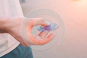 Young man holding and playing with fidget spinner.