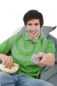 Young man holding remote control watch television