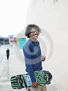 Young Man Holding Skateboard On Pavement